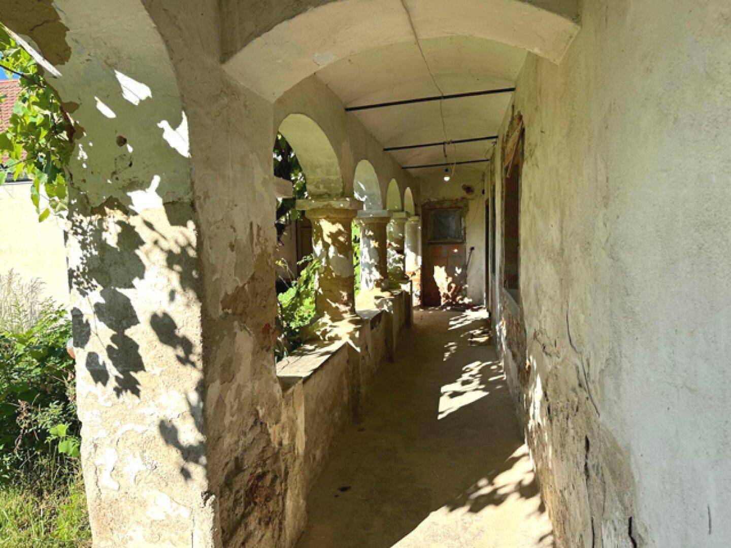 Historische Loggia mit verwitterten Säulen und Bögen, die auf eine Renovierung wartet.
