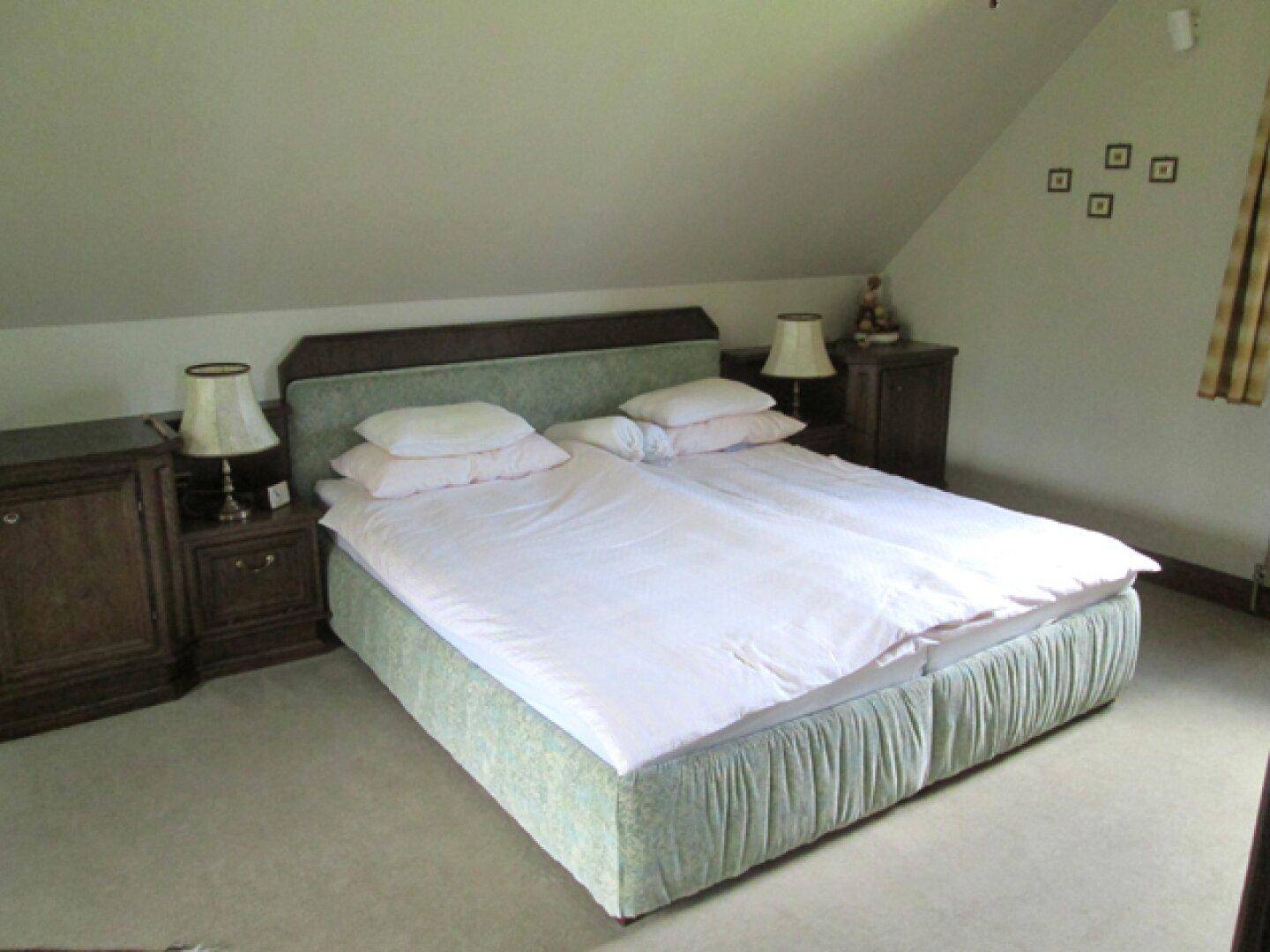 Schlafzimmer im Dachgeschoss mit Doppelbett, Teppichboden und schrägen Wänden.
