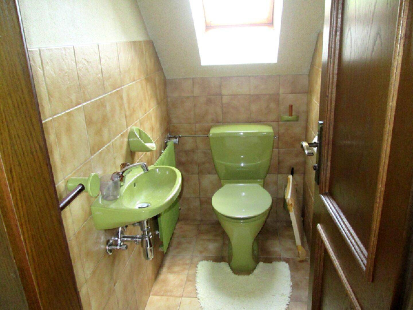 Kleines Gäste-WC im Dachgeschoss mit grüner Toilette und Waschbecken.