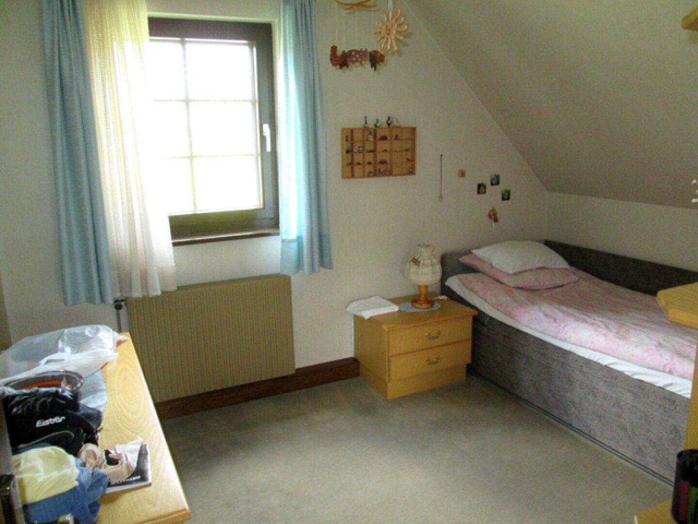 Kinder- oder Gästezimmer im Dachgeschoss mit Einzelbett und Fenster.