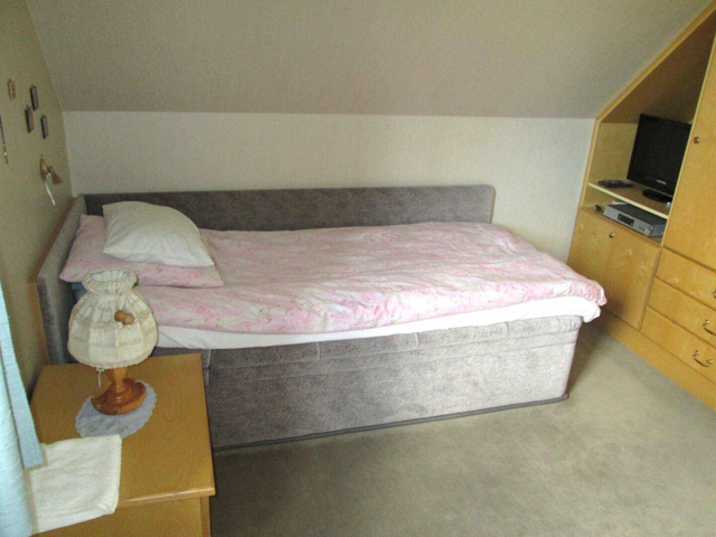 Schlafzimmer im Dachgeschoss mit Einzelbett und integriertem Schrank.