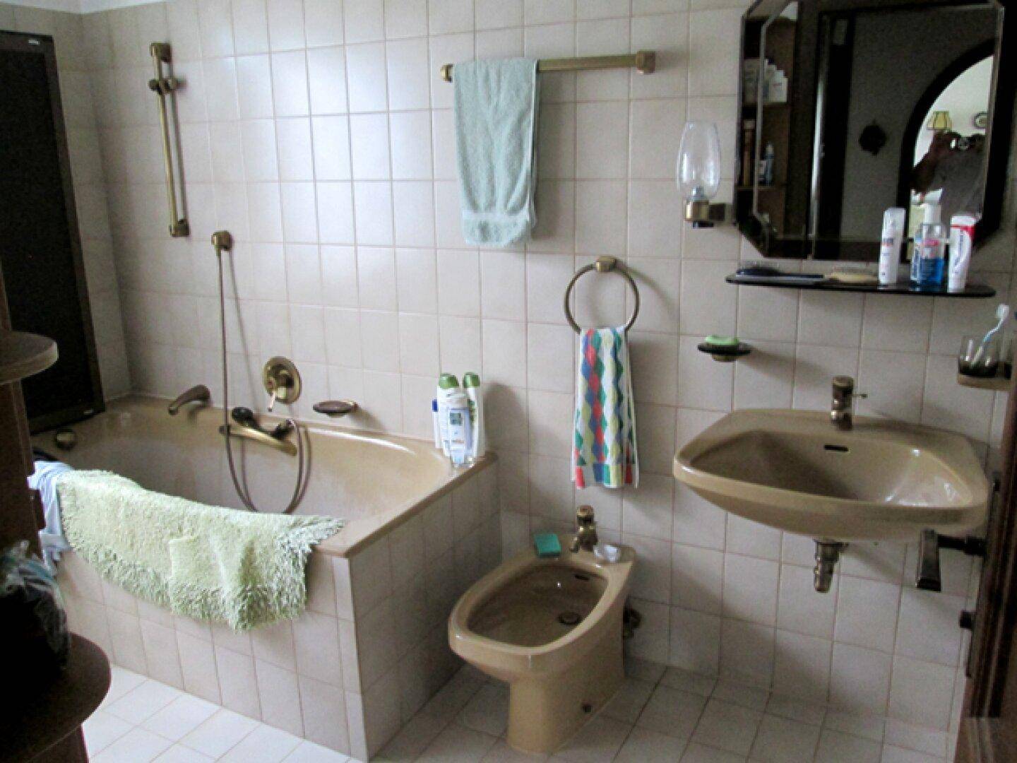 Badezimmer im 80er-Jahre-Stil mit beigefarbenen Fliesen, Badewanne und Bidet.