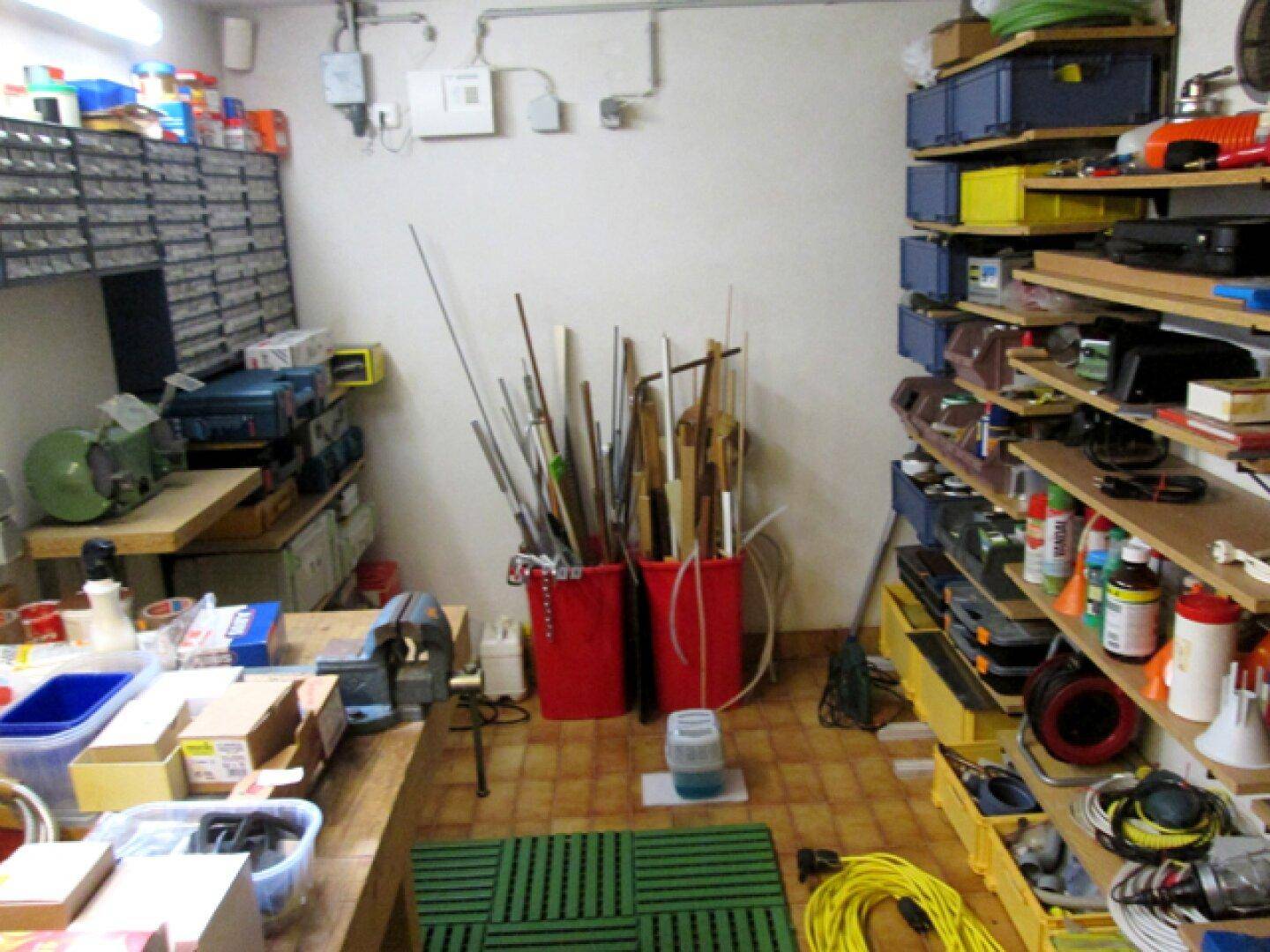 Werkstattraum im Keller mit Regalen, Werkzeugen und Materialien für verschiedene Projekte.