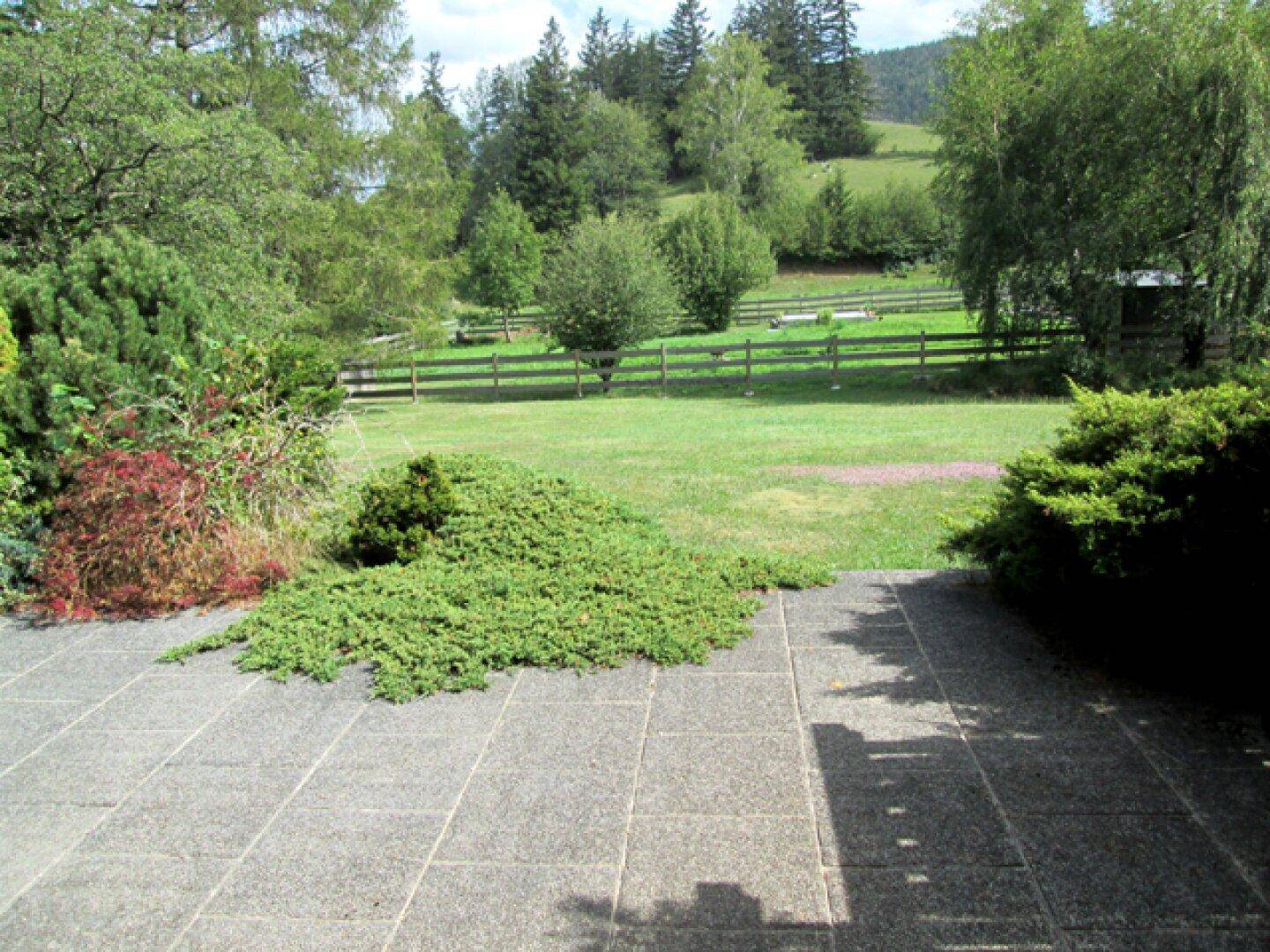 Große gepflasterte Terrasse mit weitem Blick über den Garten und die umliegende Landschaft.