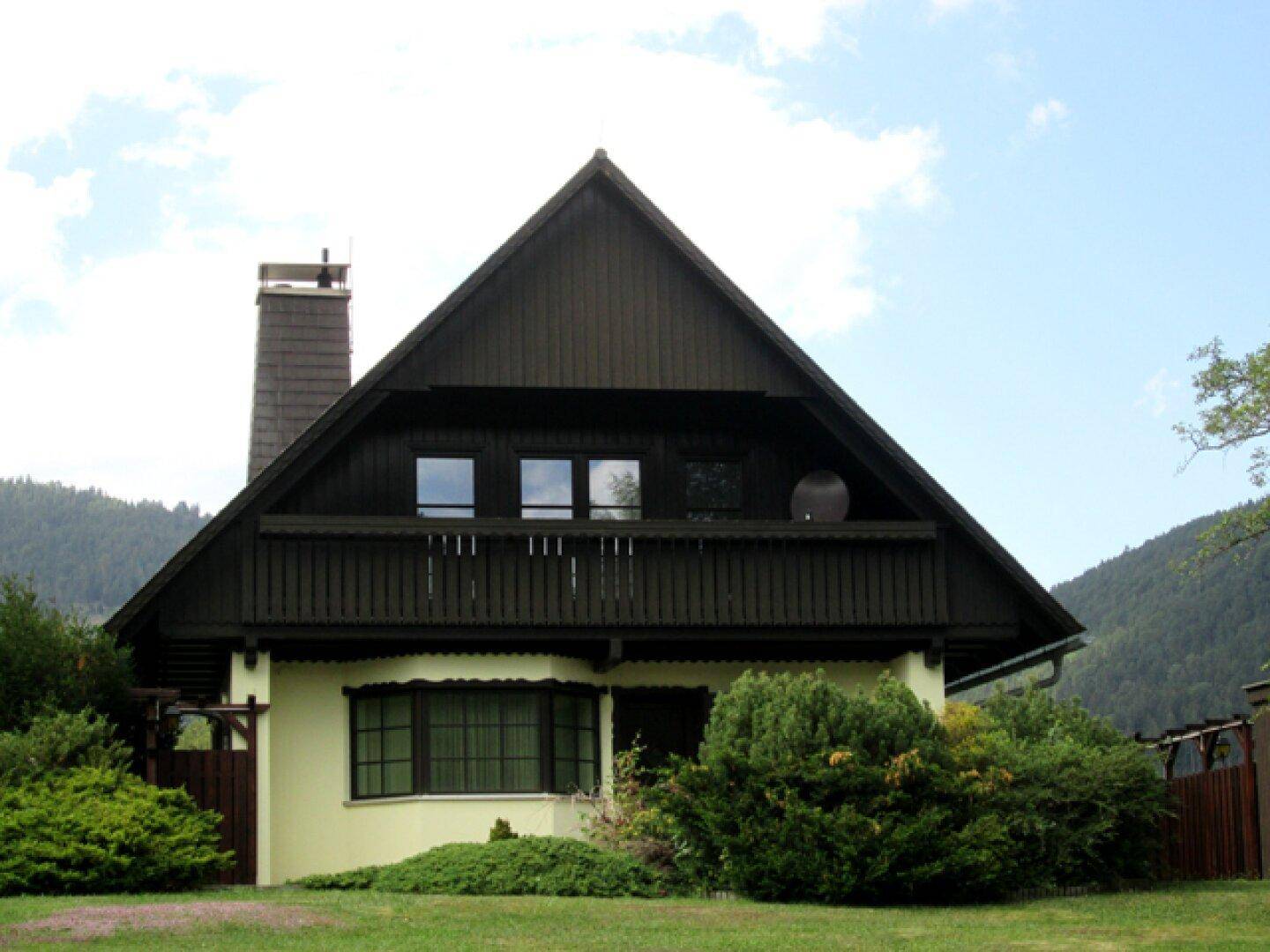 Vorderansicht eines traditionellen Hauses mit Satteldach und Balkon.