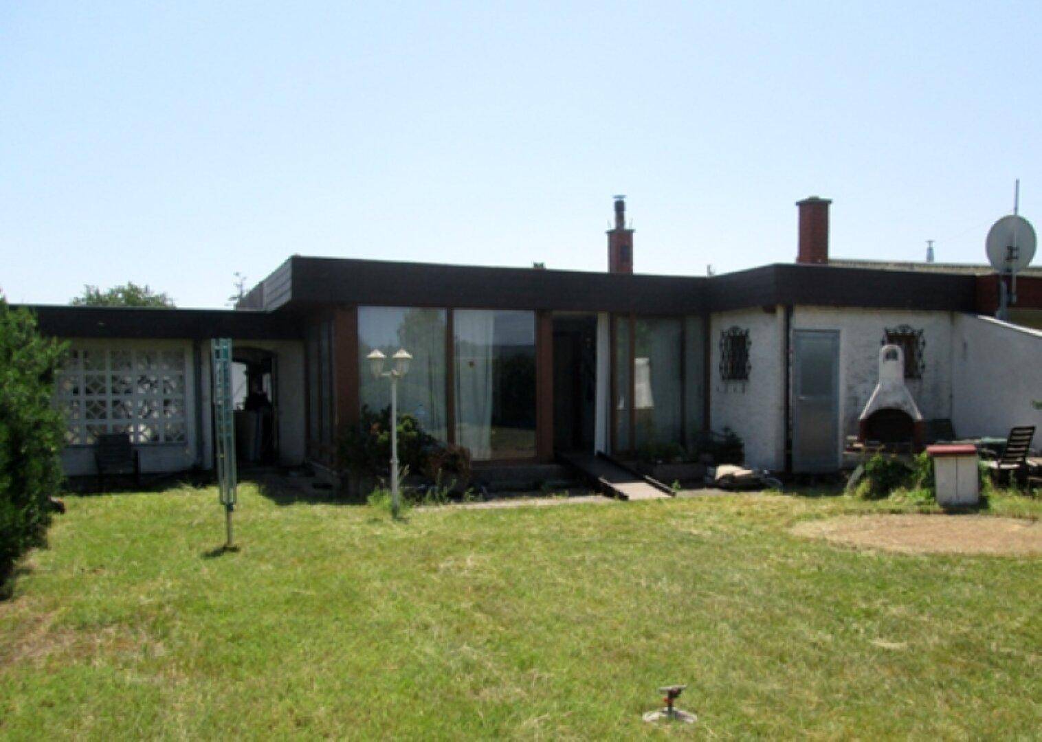 Rückansicht des Hauses mit großem Garten, Rasenfläche und einem gemauerten Grillplatz.