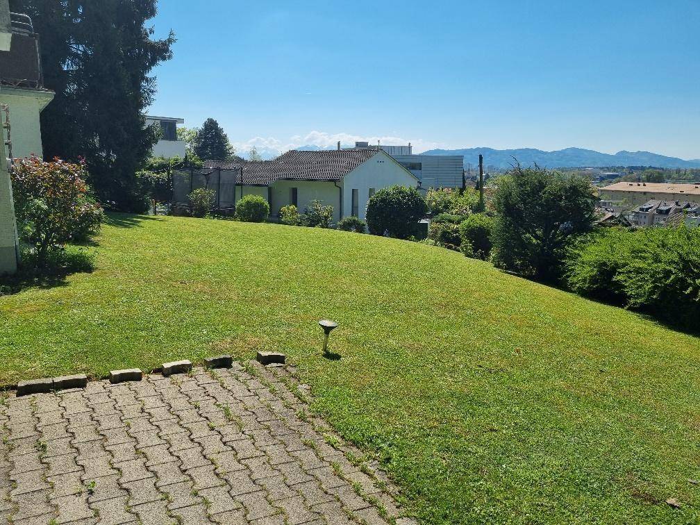 Großer, gepflegter Rasenbereich mit leichter Hanglage und Blick auf die umliegende Landschaft und Berge.