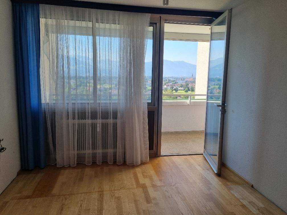 Heller Raum mit Parkettboden und Zugang zu einem Balkon mit Bergblick.
