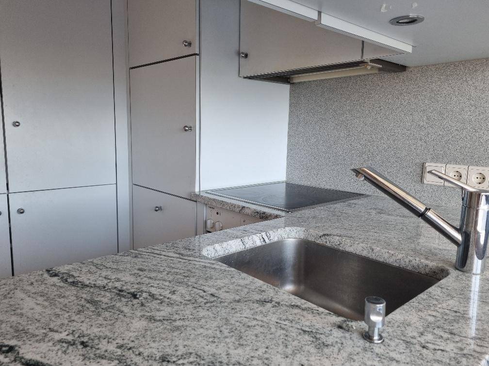 Moderne Küche mit Granitarbeitsplatte, Spüle und Induktionskochfeld.