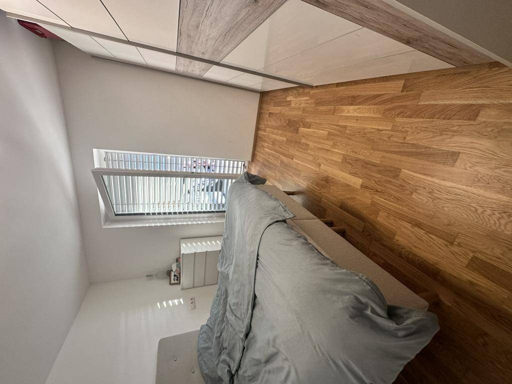 Helles Schlafzimmer mit Holzboden, großem Fenster und Einbauschrank.