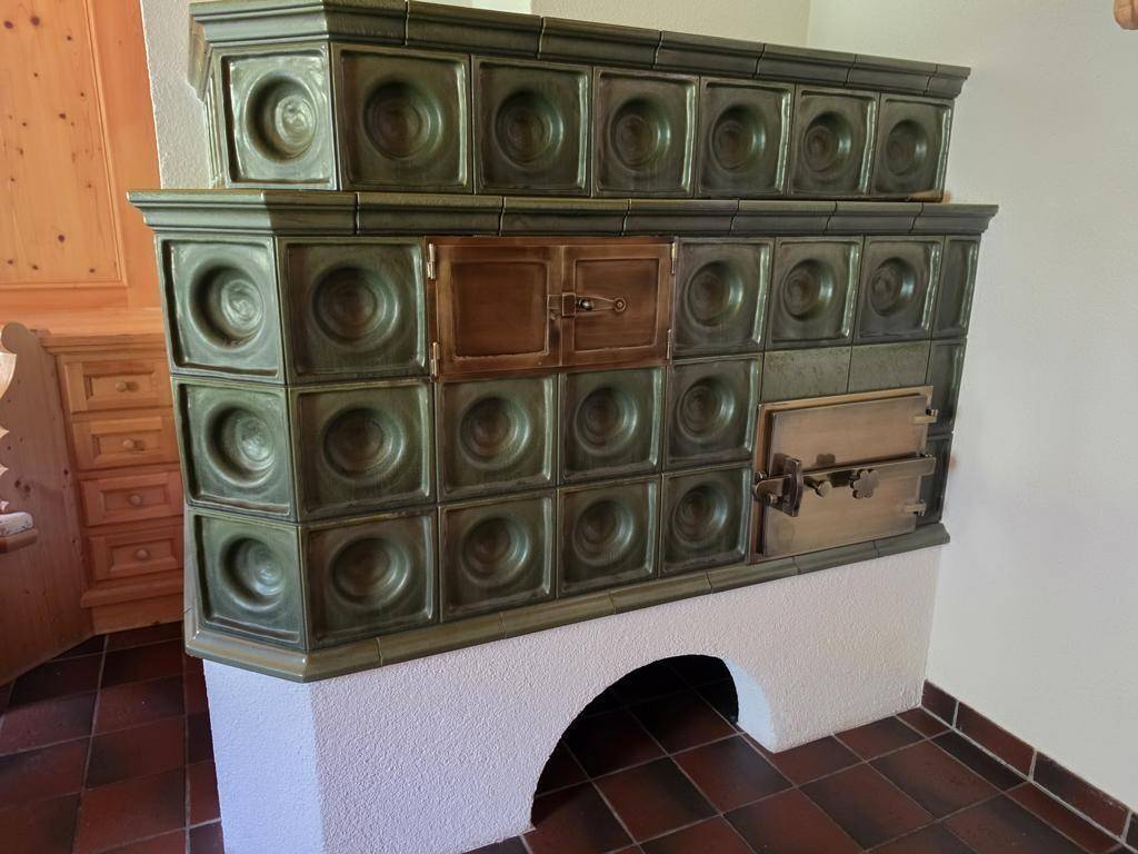 Traditioneller Kachelofen mit grünen Fliesen und rustikalem Design, der Wärme spendet.