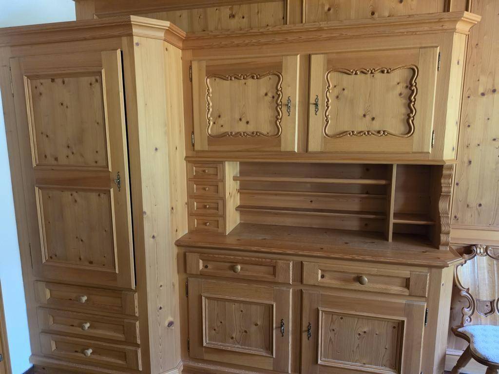 Rustikale Holzmöbel im alpenländischen Stil mit geschnitzten Details und integrierten Schränken.