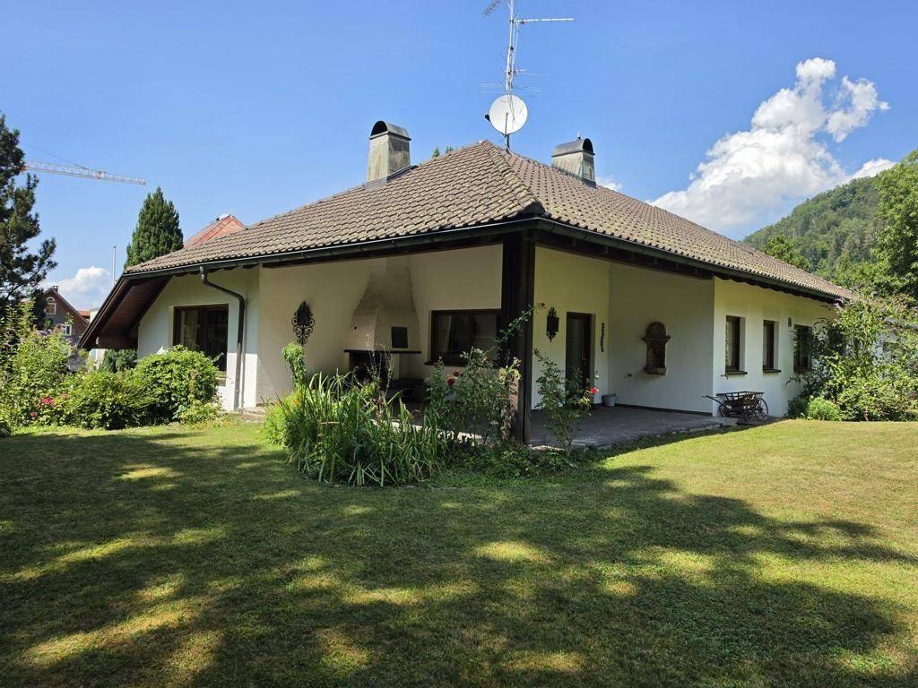Rückseite des Hauses mit großem Garten, Rasenfläche und überdachtem Außenbereich mit Grillplatz.