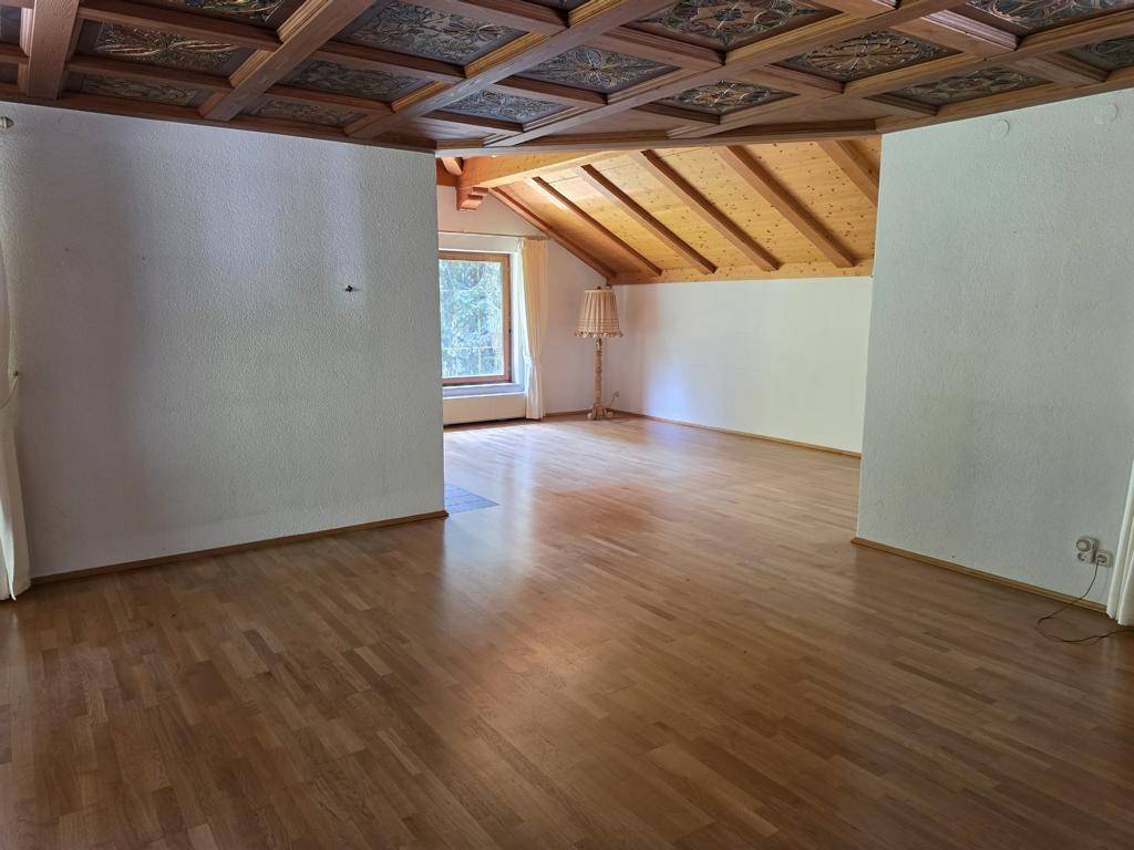 Geräumiges Wohnzimmer mit Holzboden, Kassettendecke und sichtbaren Dachschrägen, hell und einladend.