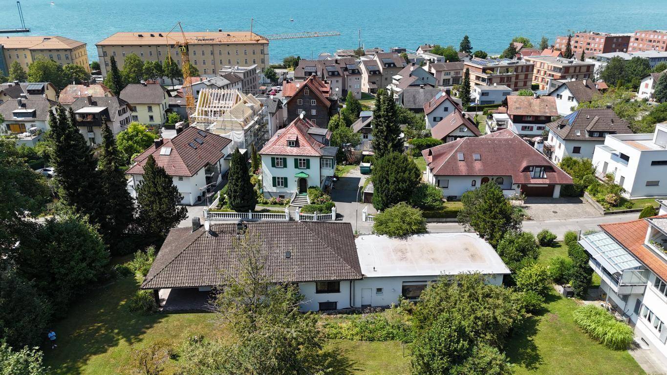 Luftaufnahme des Hauses mit umliegender Nachbarschaft und weitem Blick auf den See und die Berge.
