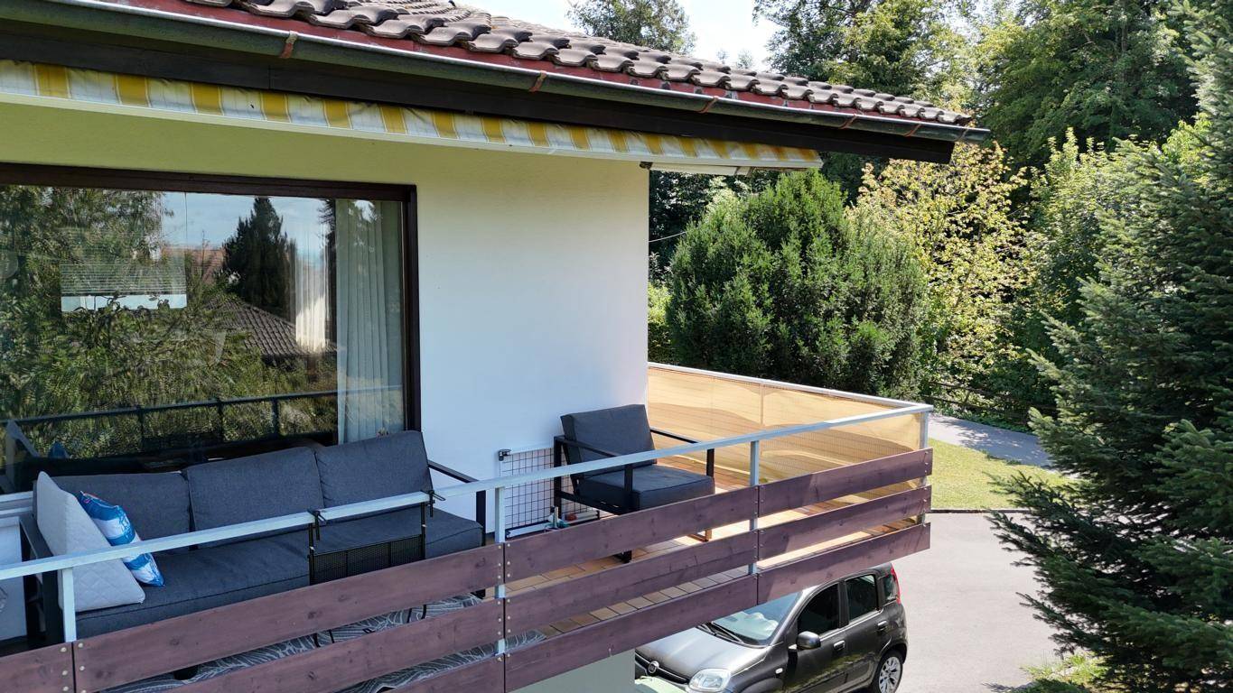 Luftaufnahme eines Einfamilienhauses mit Garten, Balkon und Parkplätzen im Grünen.