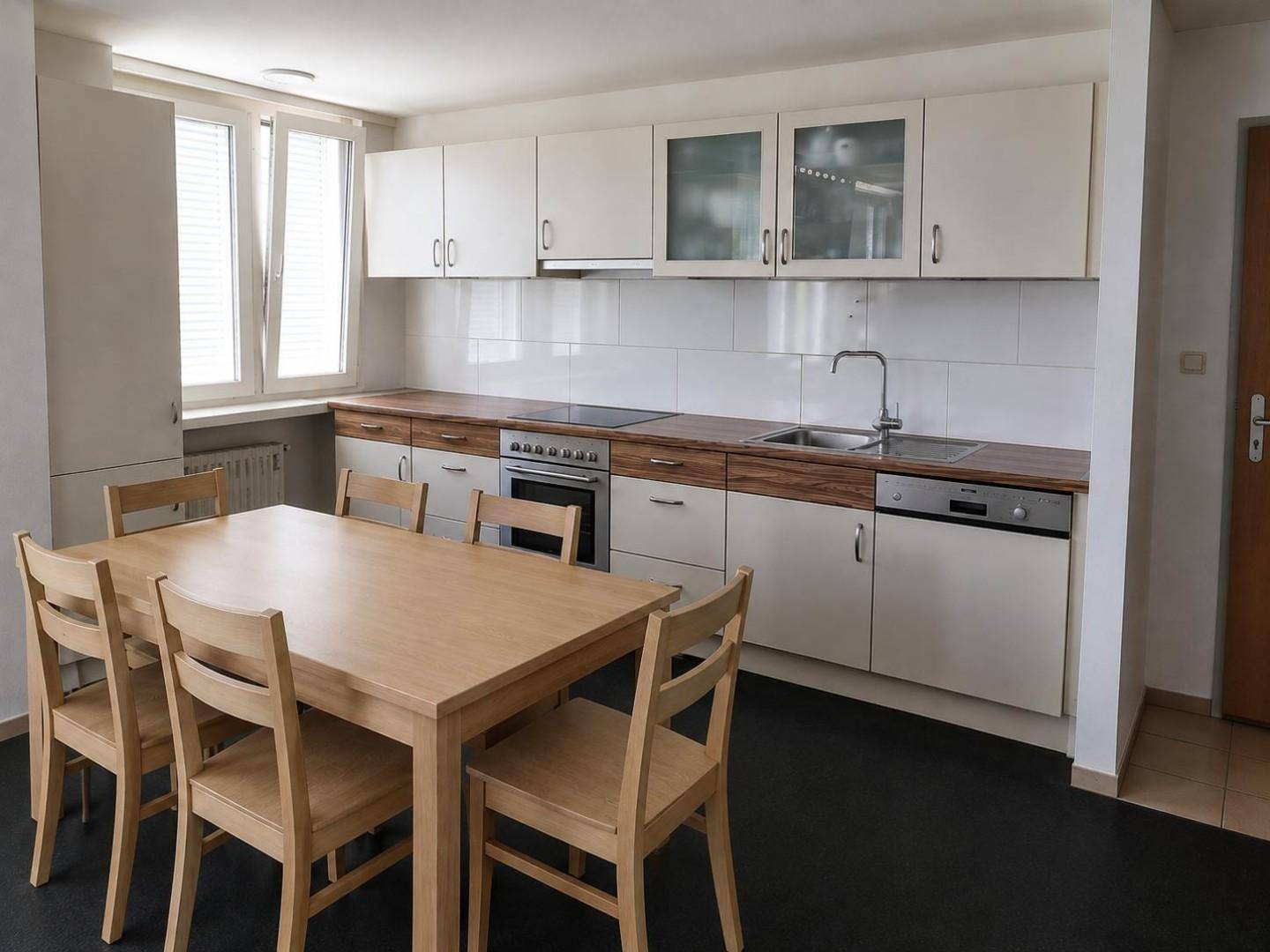 Wohnküche mit Esstisch, weißen Schränken, Holz-Arbeitsplatten und integrierten Geräten.