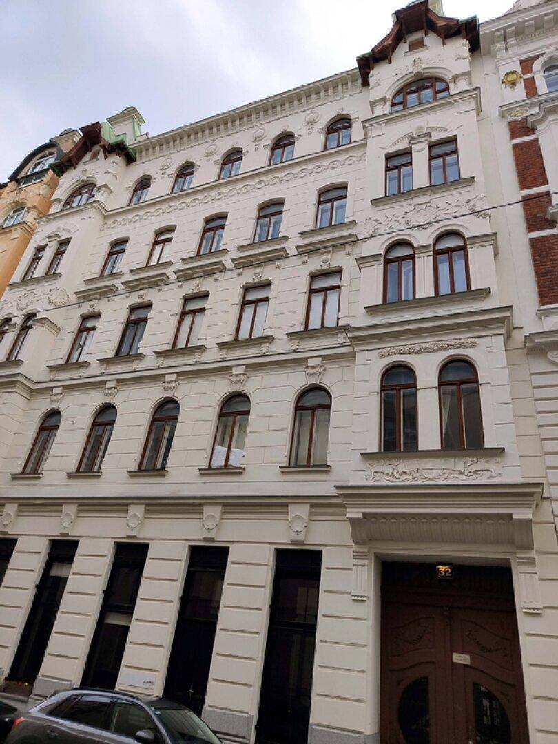 Detailansicht der historischen Fassade eines Altbaus mit verzierten Fenstern.