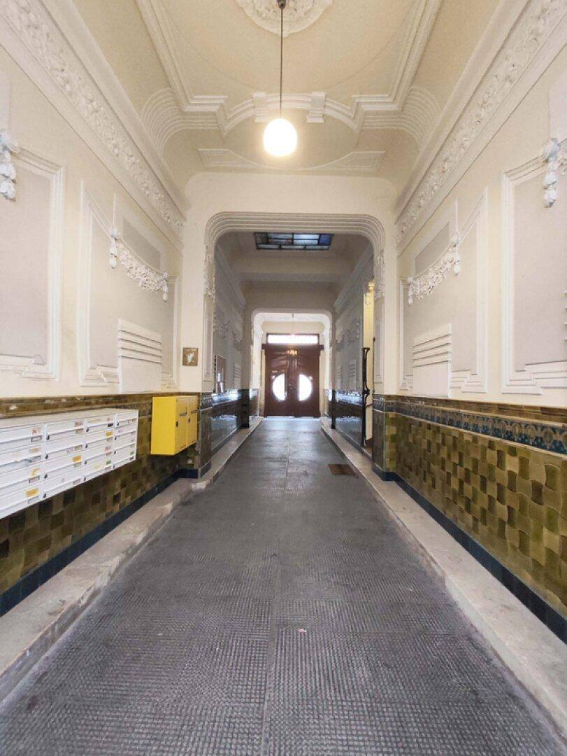 Eindrucksvoller Eingangsbereich mit hohen Decken, Stuckverzierungen und historischen Fliesen.