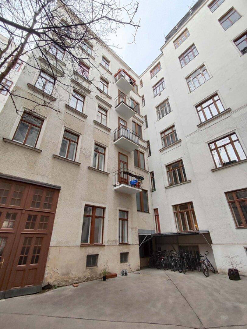 Hinterhof eines Mehrfamilienhauses mit Balkonen, Fahrradabstellplatz und Garagentor.