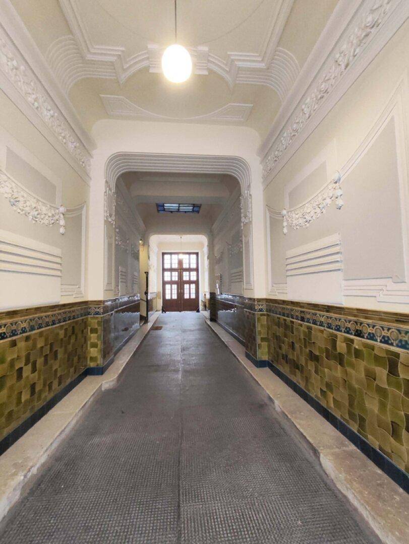 Langer Eingangsbereich mit dekorativen Wandfliesen und Stuckelementen an der Decke.