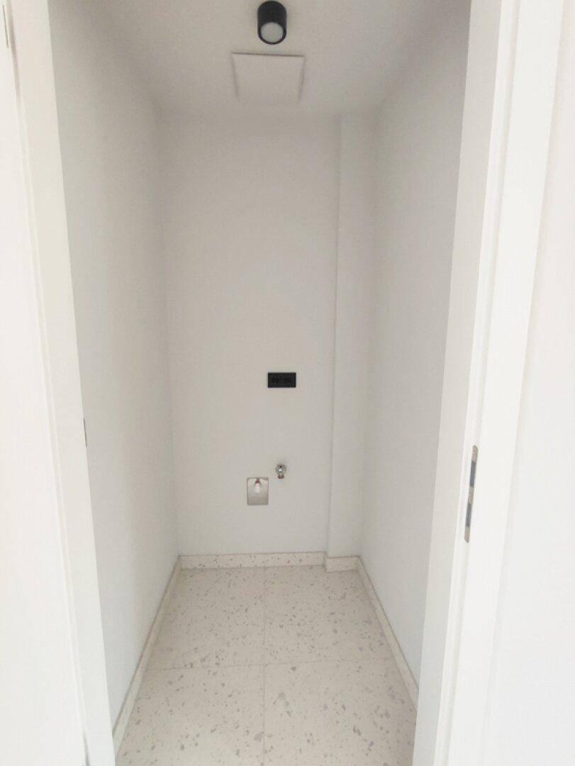 Kleiner Hauswirtschaftsraum mit Fliesenboden und Anschlüssen für eine Waschmaschine.