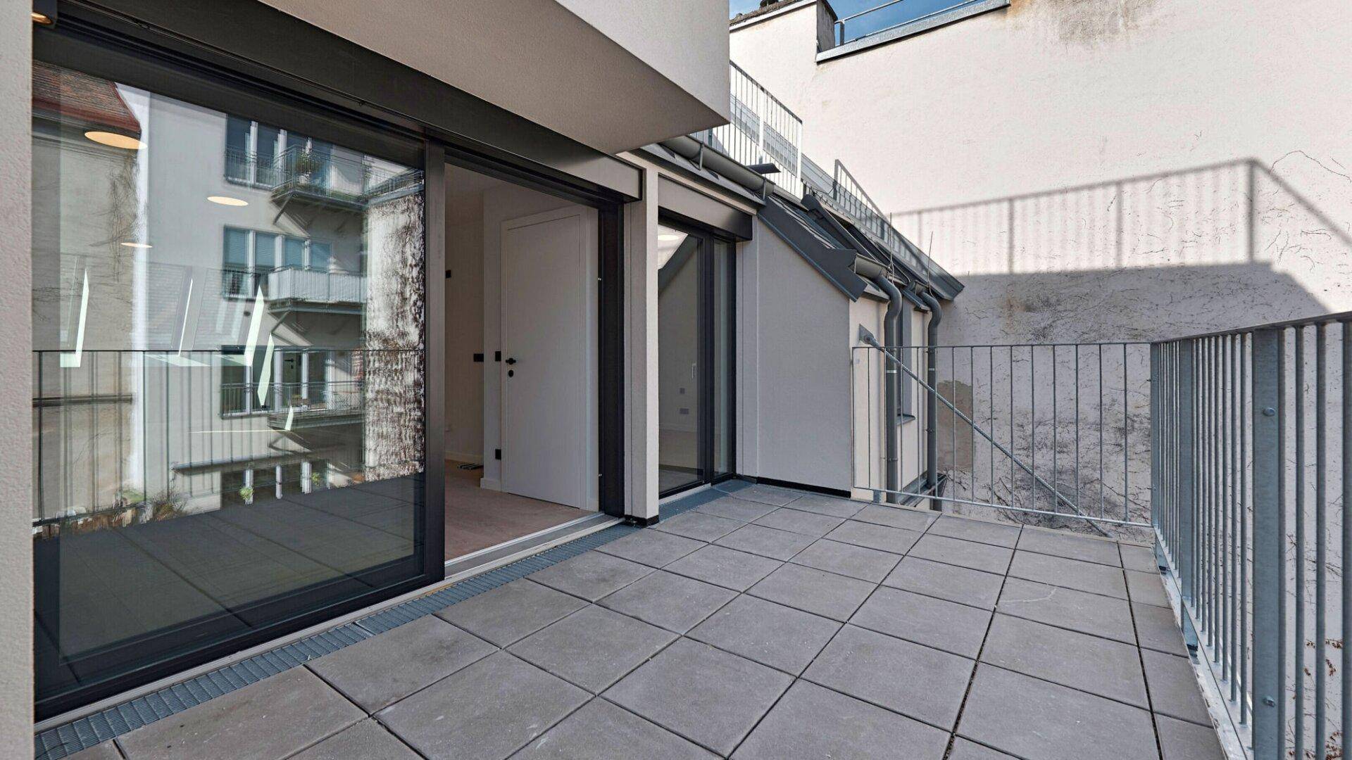 Geräumige Dachterrasse mit modernen Fliesen und Blick auf die umliegenden Dächer der Stadt.