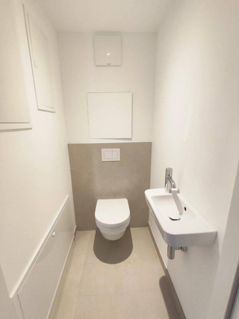 Modernes Gäste-WC mit wandhängender Toilette und kleinem Waschbecken.