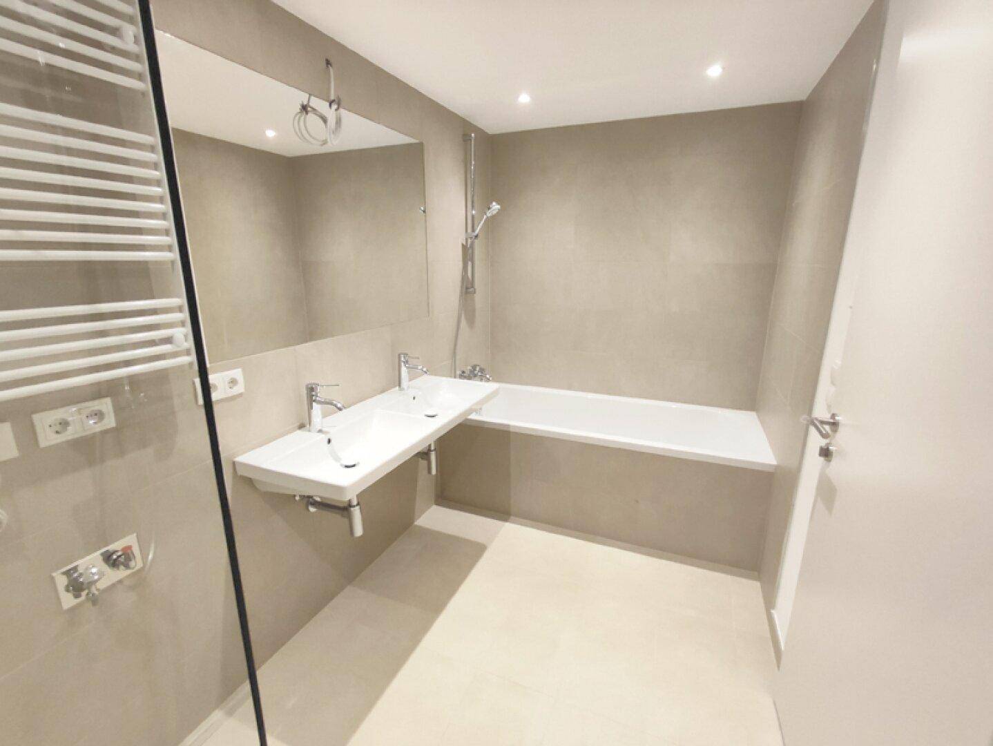Geräumiges modernes Badezimmer mit Badewanne, ebenerdiger Dusche und Doppelwaschbecken.