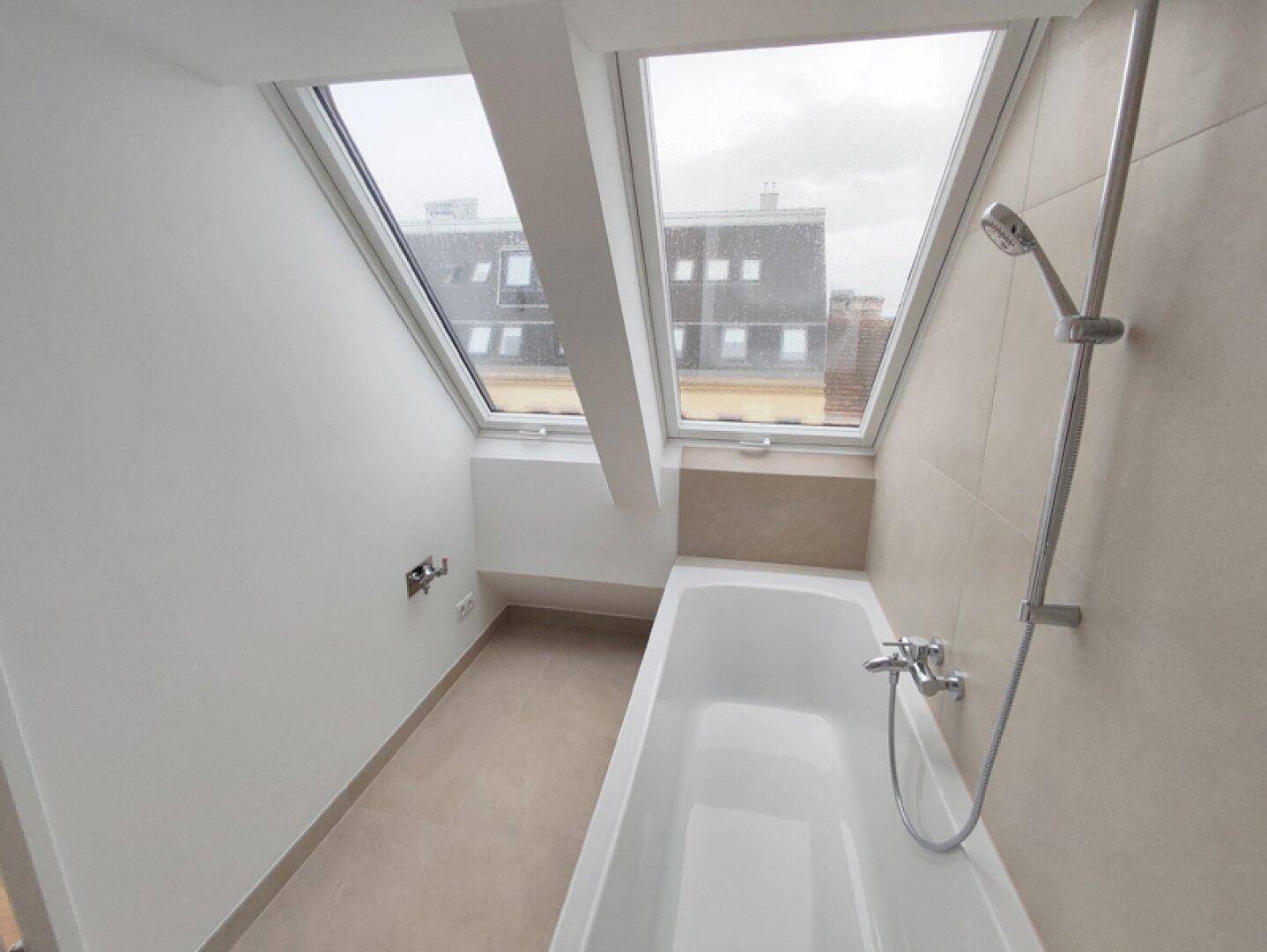 Helles Badezimmer mit Badewanne und Dachfenstern, die viel Tageslicht hereinlassen.