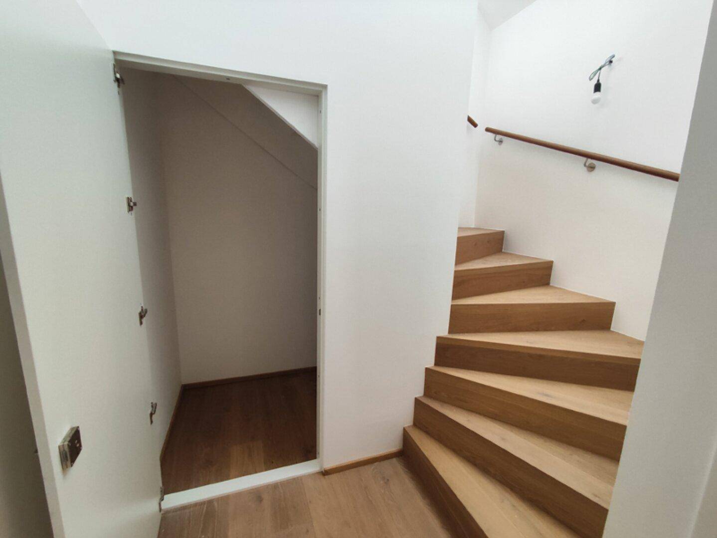 Praktischer Stauraum unter der Treppe mit Holzboden und einfacher Zugangstür.