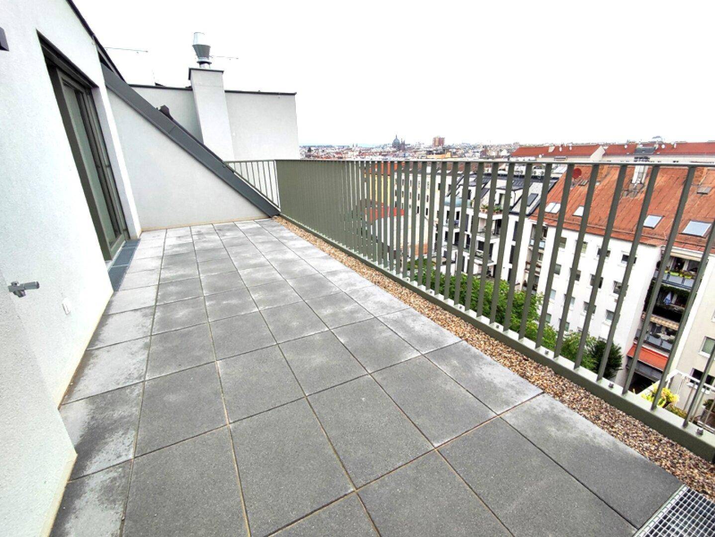 Geräumige Dachterrasse mit Fliesenboden und weitem Blick über die Stadt.