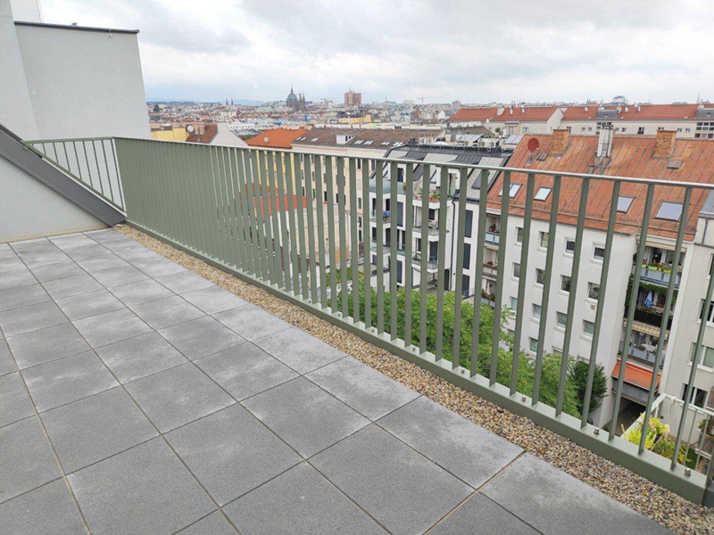 Weitläufige Dachterrasse mit Fliesen und Panoramablick über die Dächer der Stadt.