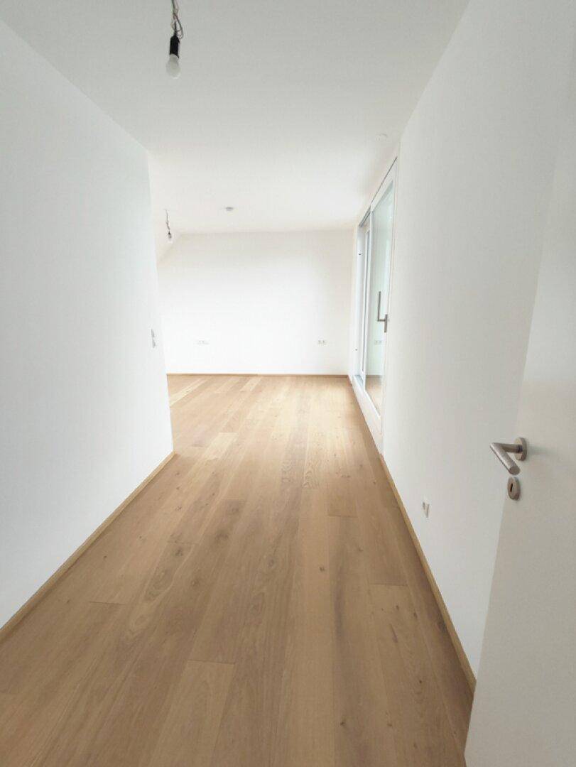 Langer, heller Flur mit Holzboden, der zu weiteren Räumen führt.