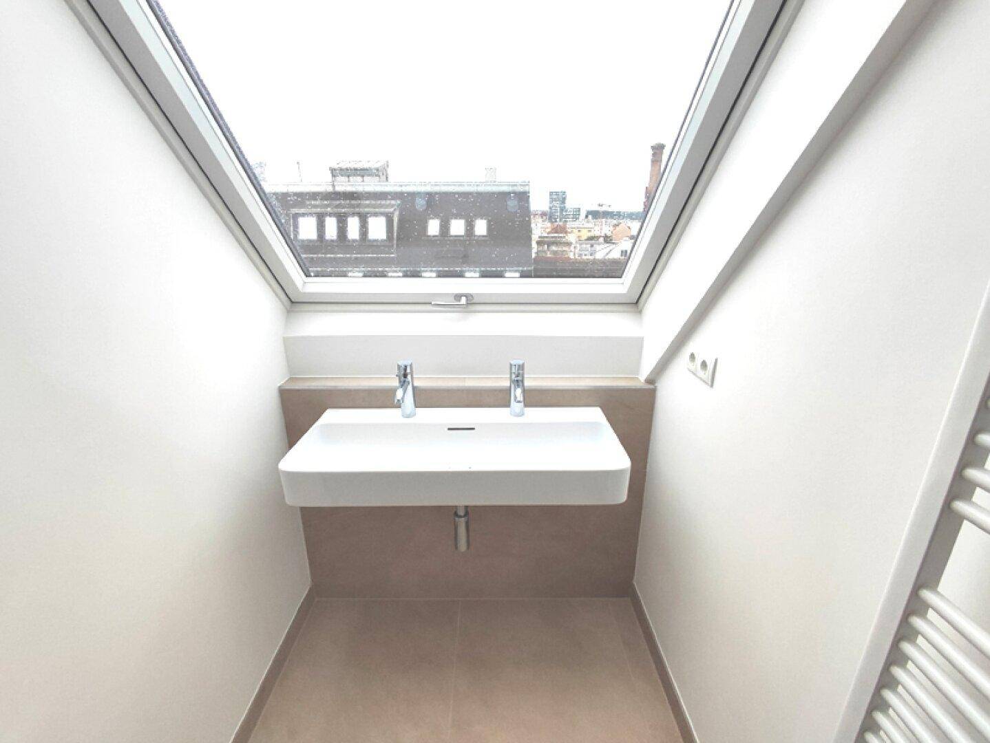 Modernes Badezimmer mit Doppelwaschbecken und großem Dachfenster unter einer Dachschräge.