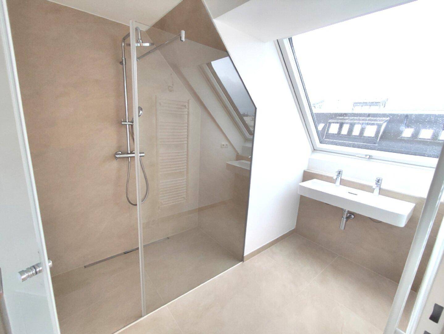 Geräumiges Badezimmer mit moderner Dusche, Doppelwaschbecken und Dachfenstern.