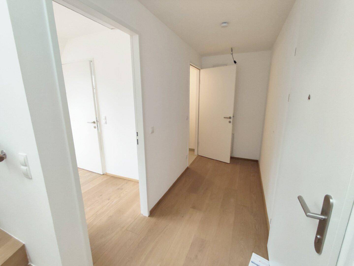 Heller Flur mit mehreren Türen, die zu verschiedenen Zimmern führen.