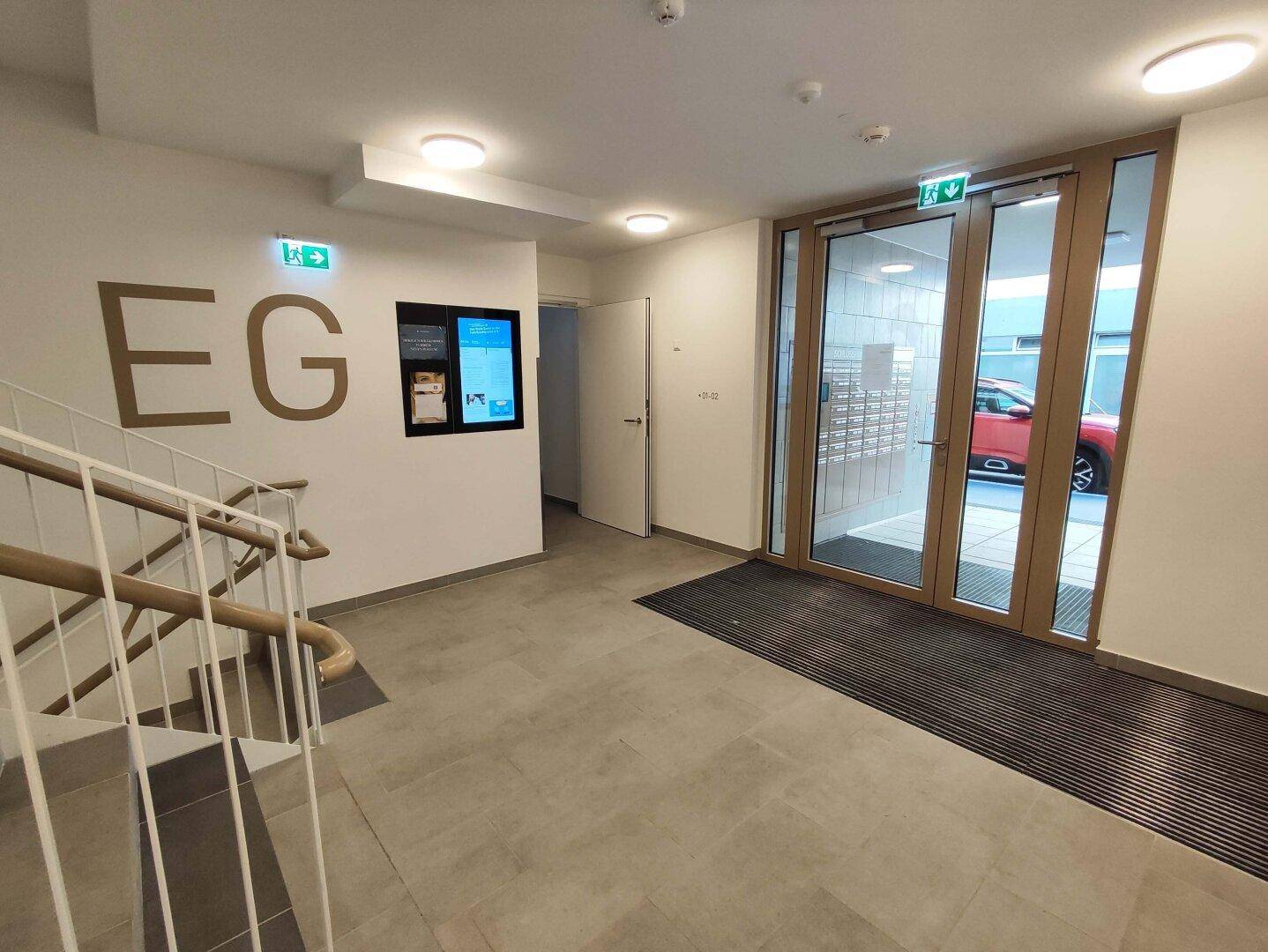 Heller Eingangsbereich mit Treppenaufgang und Zugang zu den Wohnungen im Erdgeschoss.