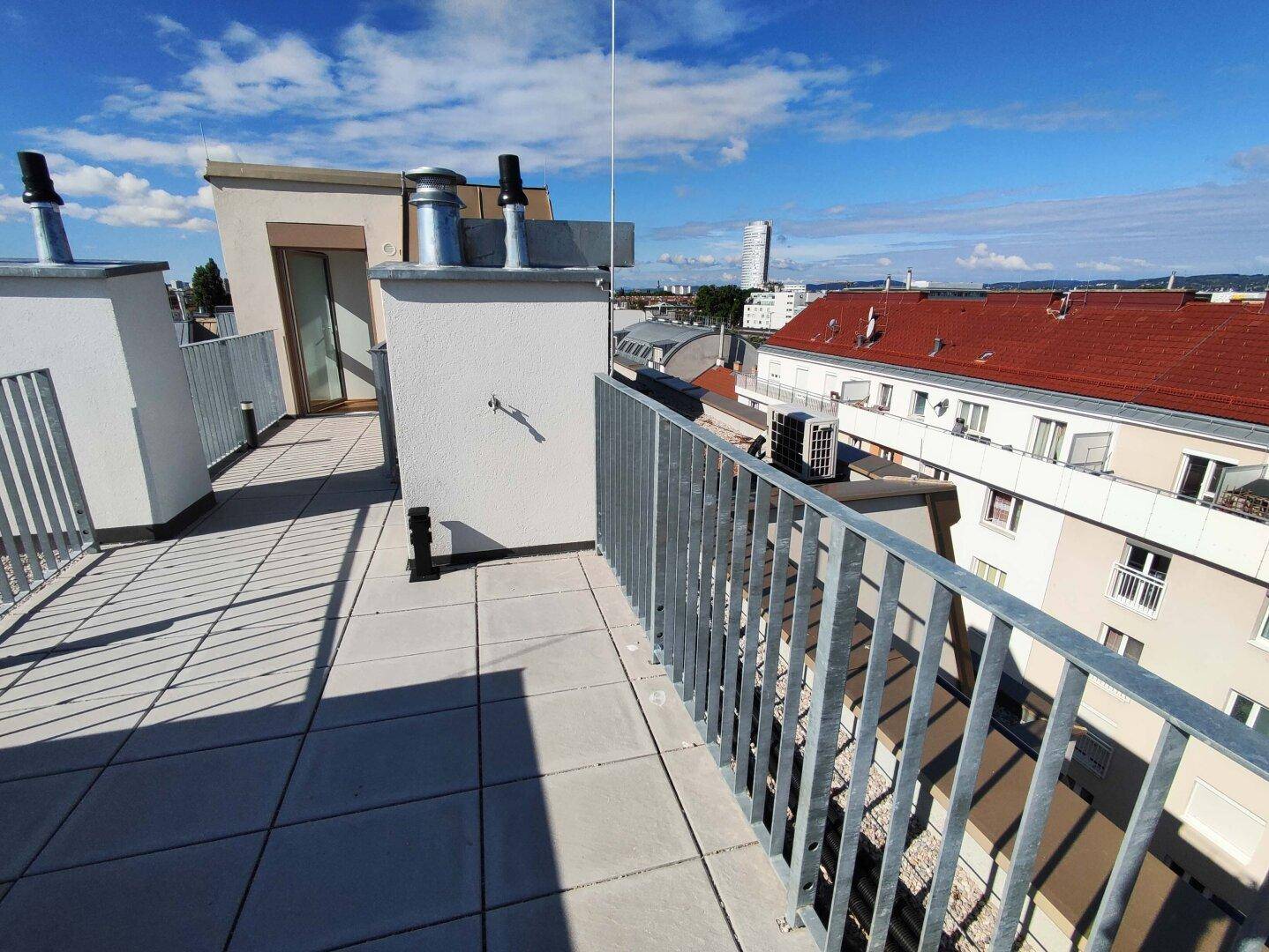 Dachterrasse mit Fliesenboden und Metallgeländer bietet einen weiten Blick über die Stadt.
