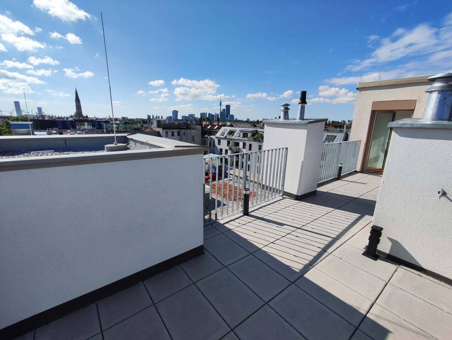 Dachterrasse mit Fliesenboden und Metallgeländer bietet einen weiten Blick über die Stadt.