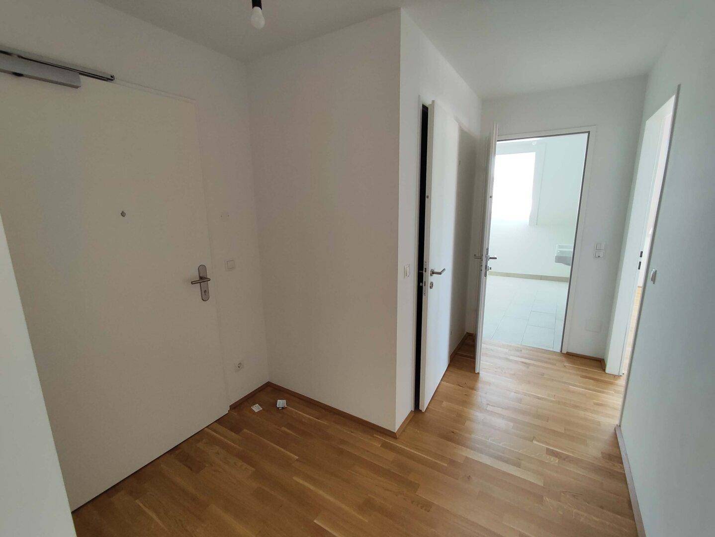 Heller Flur mit Holzboden und mehreren Türen, der verschiedene Räume der Wohnung verbindet.