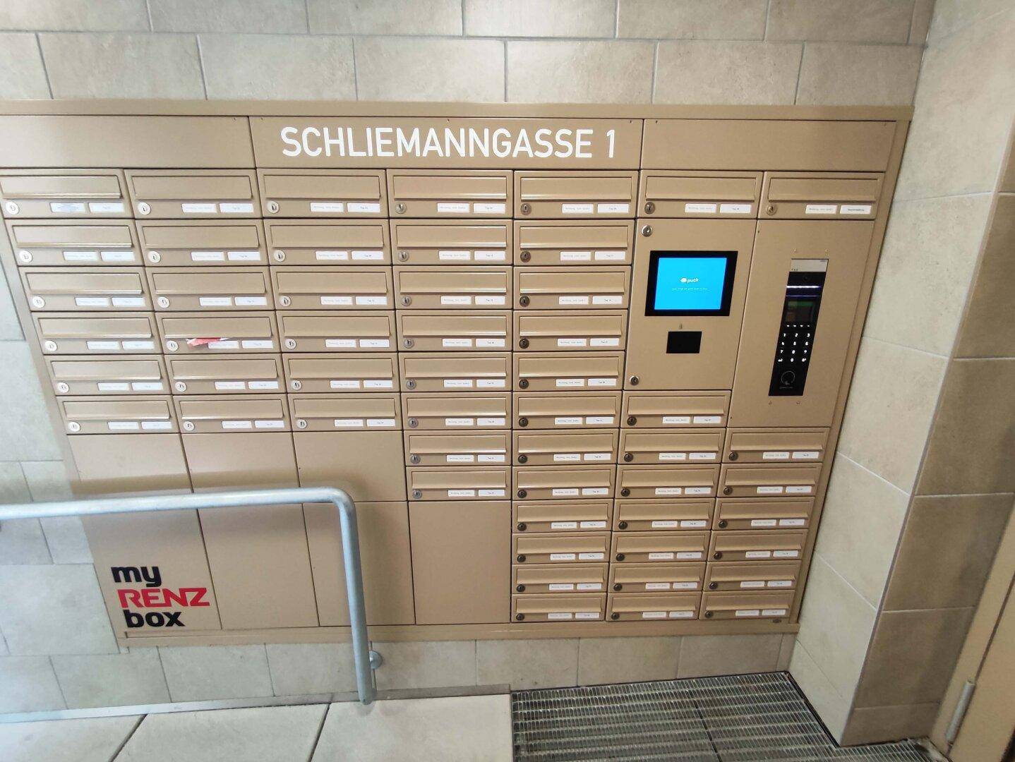 Detaillierte Ansicht der modernen Briefkastenanlage mit digitalem Display im Eingangsbereich.