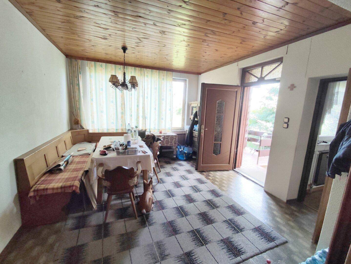 Essbereich mit Holztisch, Eckbank, Holzdecke und Zugang zu einem Außenbereich.