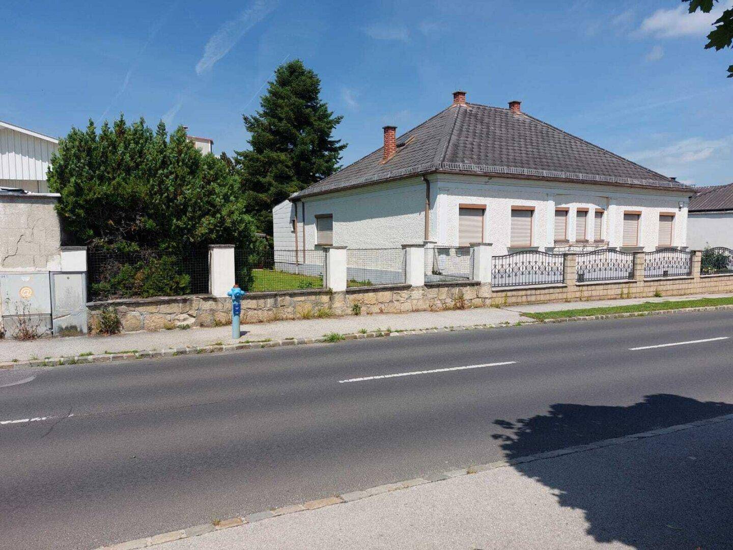 Hausfassade von der Straße aus gesehen mit Rollläden und einem gepflegten Vorgarten.