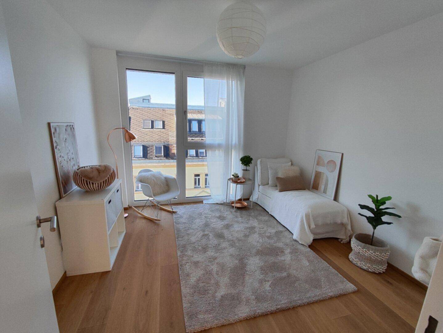 Helles Schlafzimmer mit Tagesbett, Holzboden und großem Fenster.