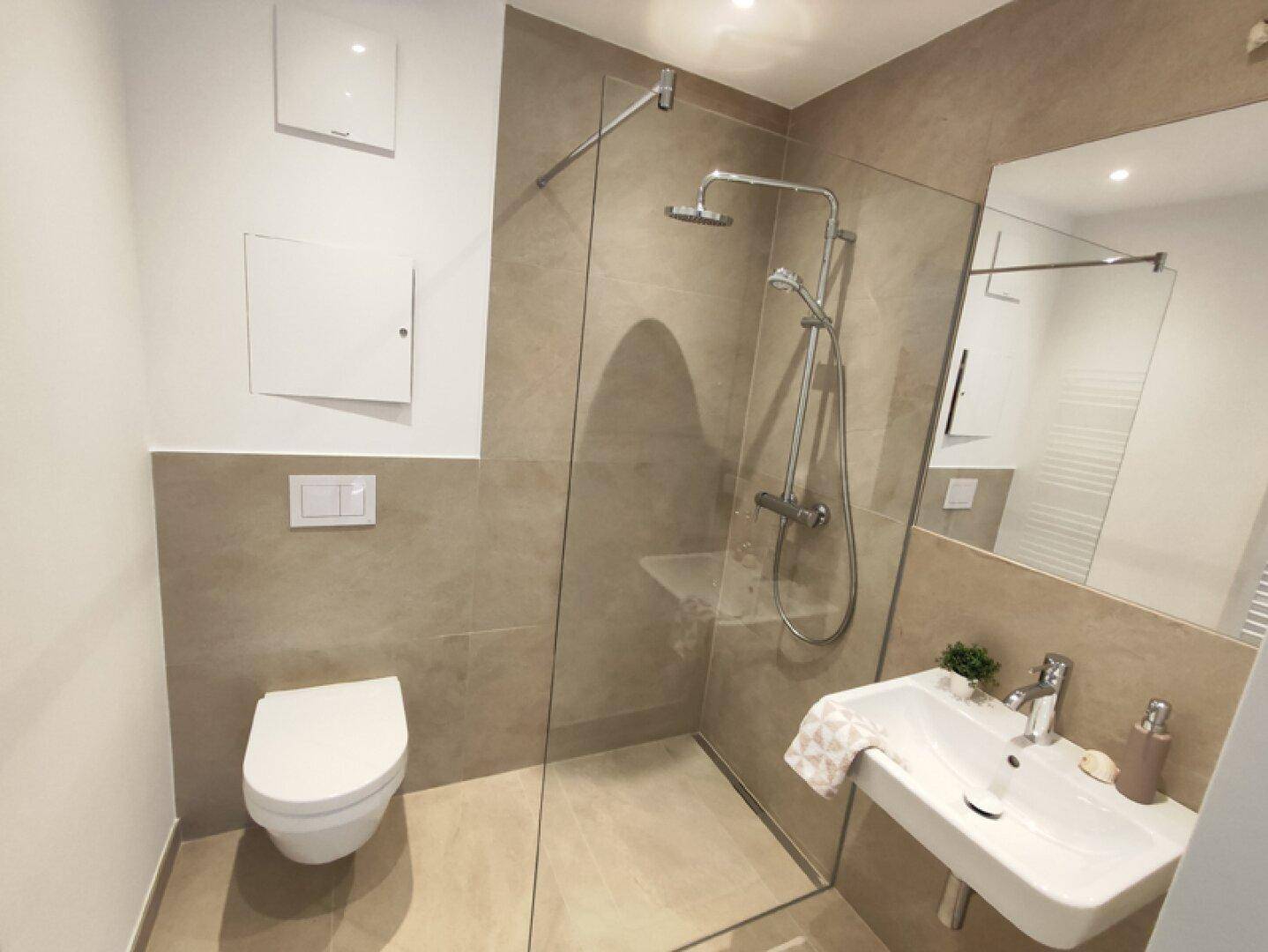 Modernes Badezimmer mit ebenerdiger Dusche, Wand-WC und beigefarbenen Fliesen.