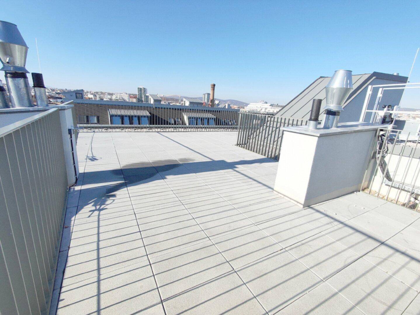 Geräumige Dachterrasse mit Fliesenboden und weitem Blick über die Stadt.