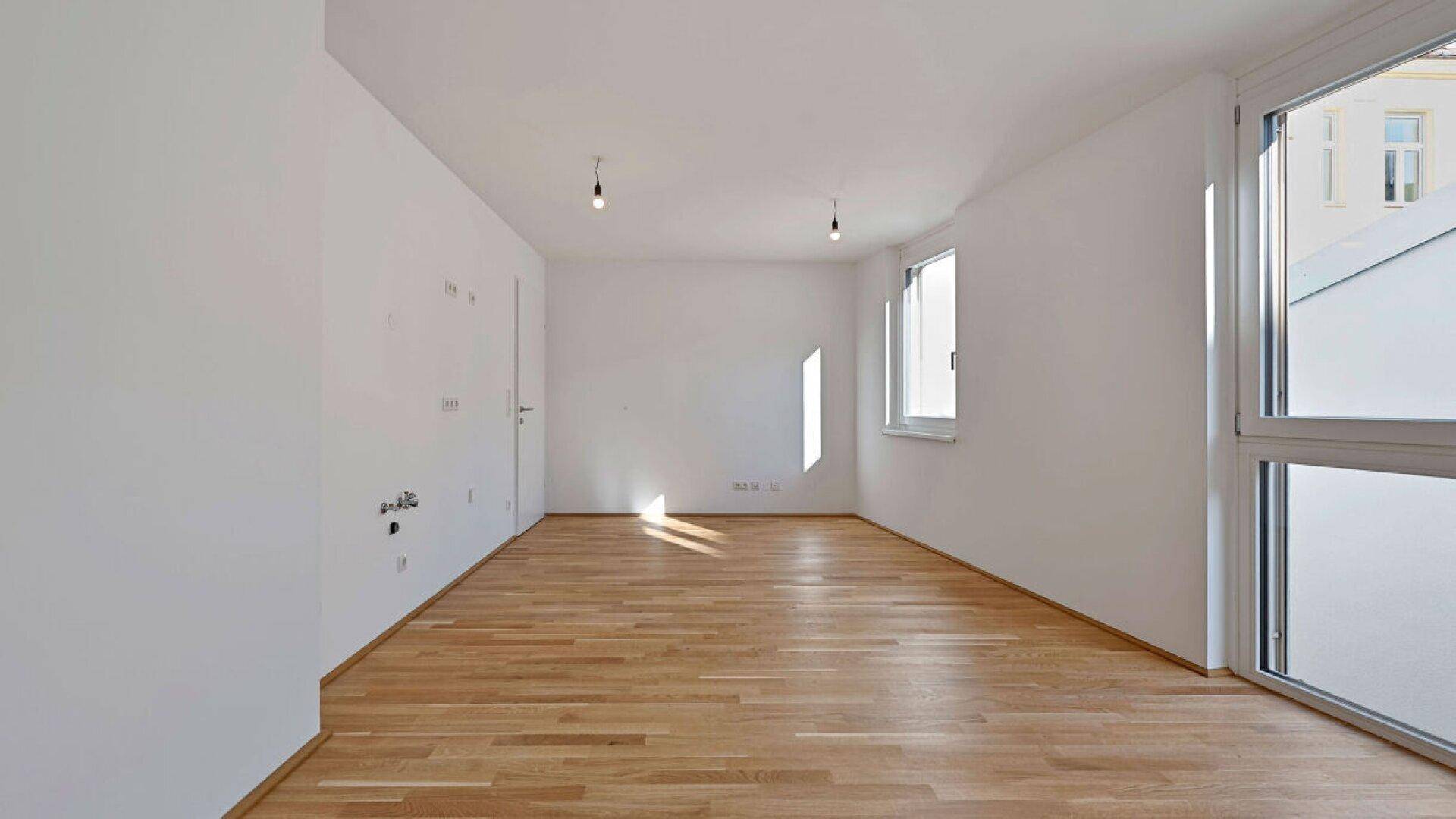 Heller Wohnraum mit Parkettboden und großen Fenstern für viel Tageslicht.
