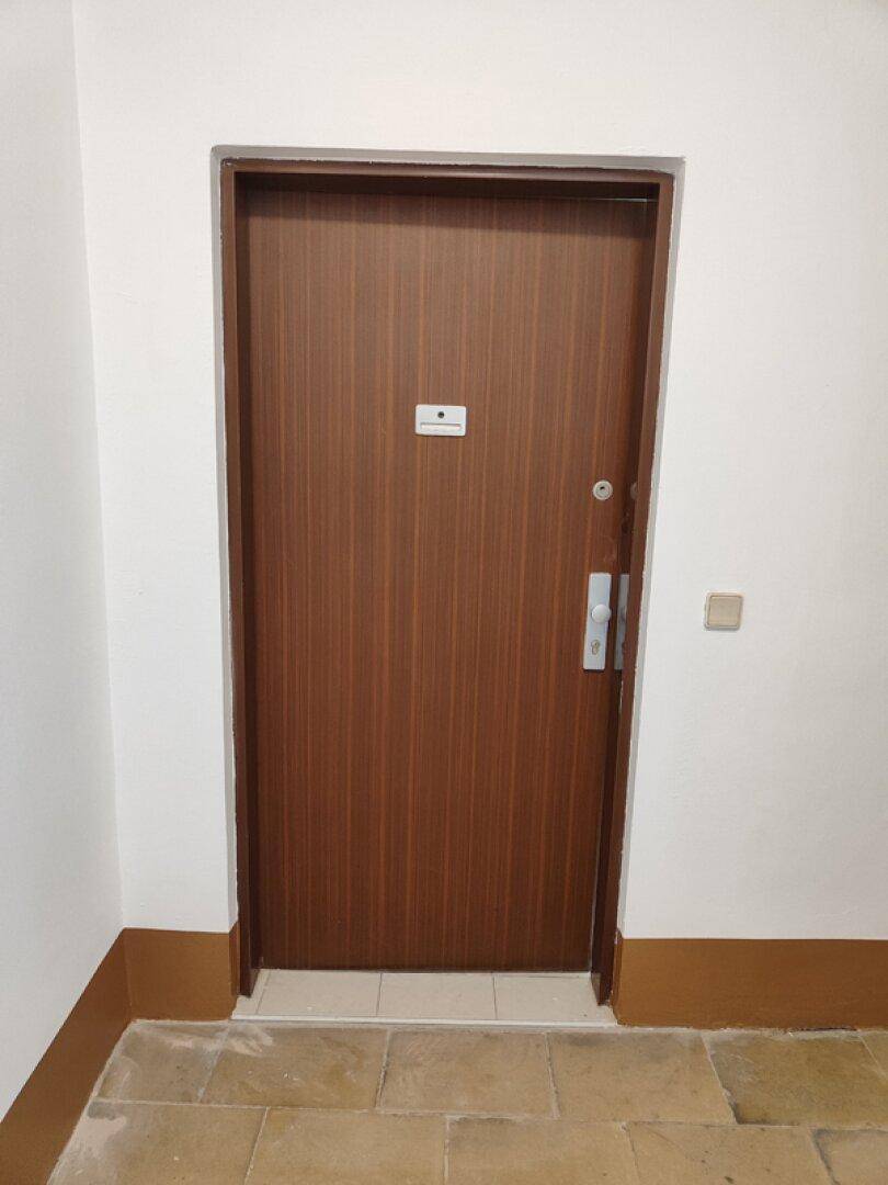 Robuste Holztür zum Eingang der Wohnung, mit einem kleinen Namensschild.