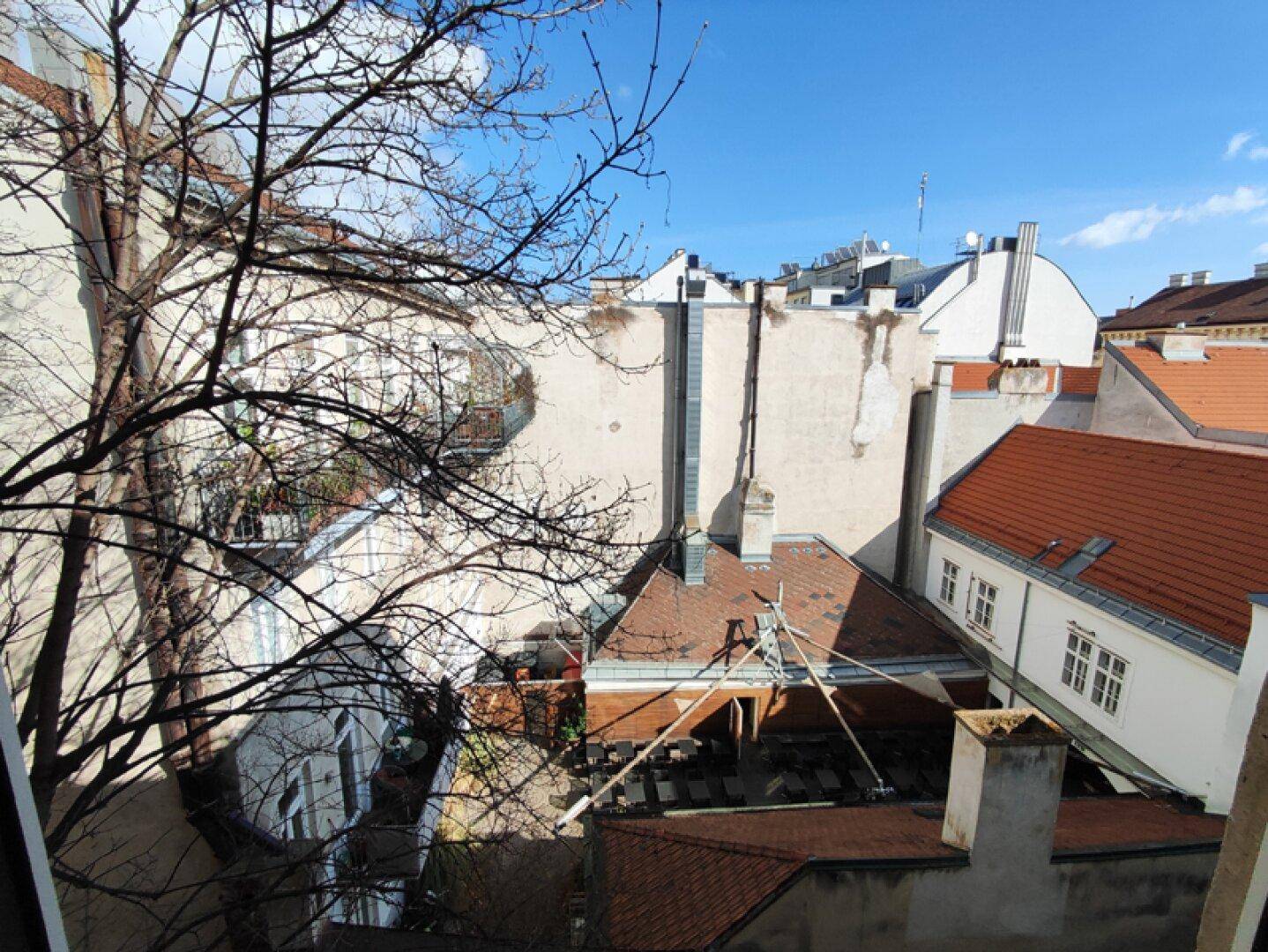 Blick aus dem Fenster über die Dächer der umliegenden Gebäude und einen Innenhof.